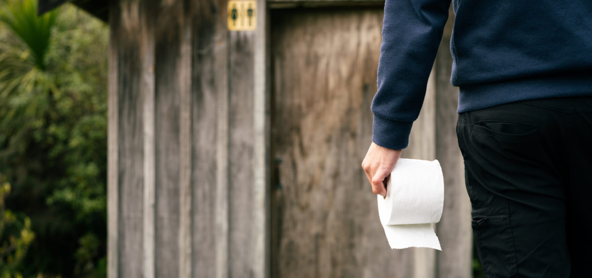 Une personne allant utiliser avec un rouleau de papier hygiénique dans la main